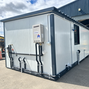 Rear and side view of an 8.08m x 3m portable cabin with exterior plumbing and a gas water heater